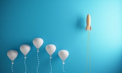 Rocketship outracing a group of hot air balloons to represent how we succeed in speed and quality as a benefit of recruitment process outsourcing