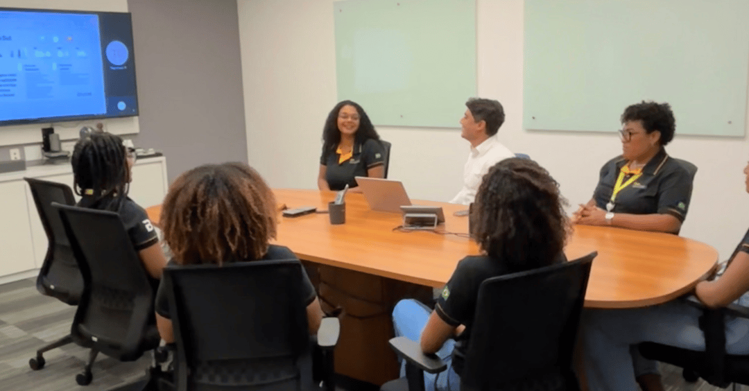 The young women who make up our second cohort of apprentices gather around a conference table to learn about our energy recruitment services in Brazil