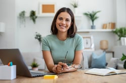 Woman at office smiles and looks at camera. Many mid-to-senior level professionals like her search for how to build a personal brand. Brunel's 8-step guide has them covered.