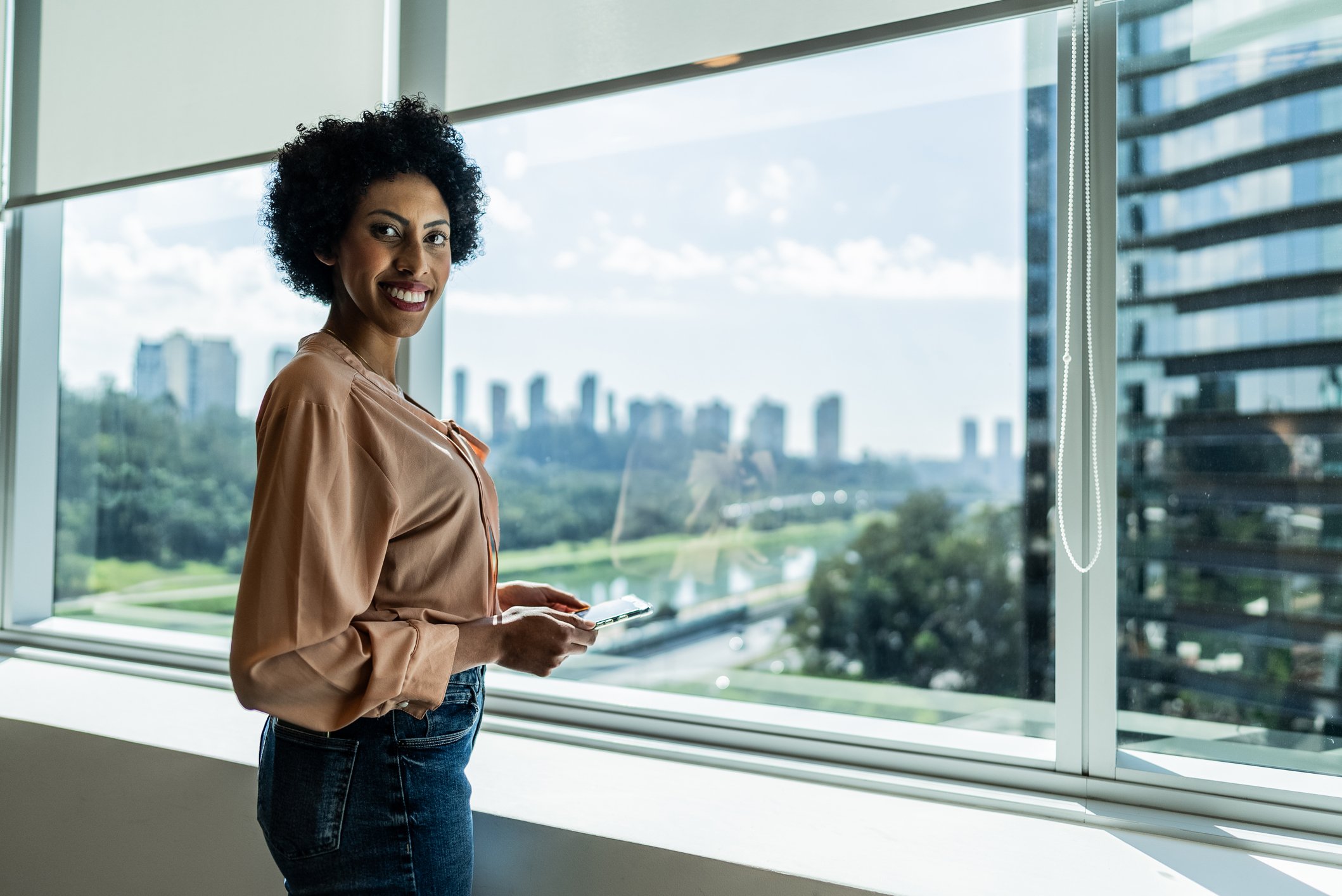 Woman stands in front of office window in Sao Paulo. Brunel is expanding among recruitment agencies in Sao Paulo