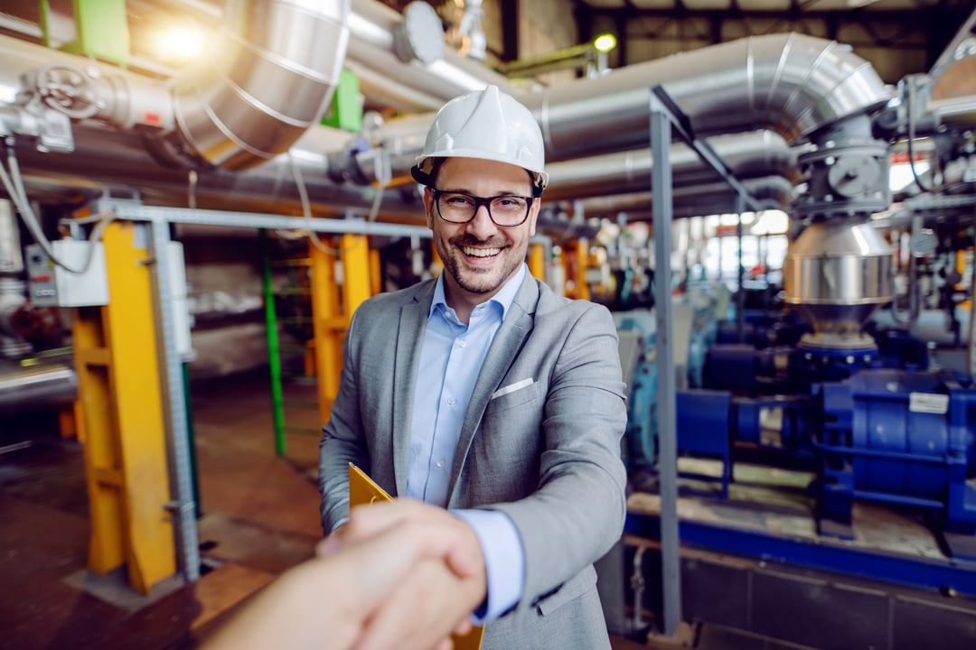 energy recruitment professional smiles as he shakes hands at a chemical refinery