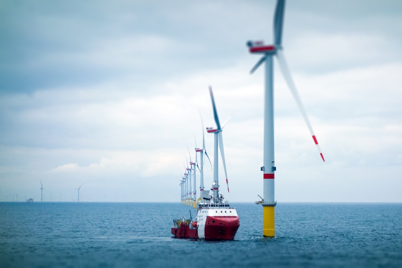 A boat next to wind turbines on the ocean