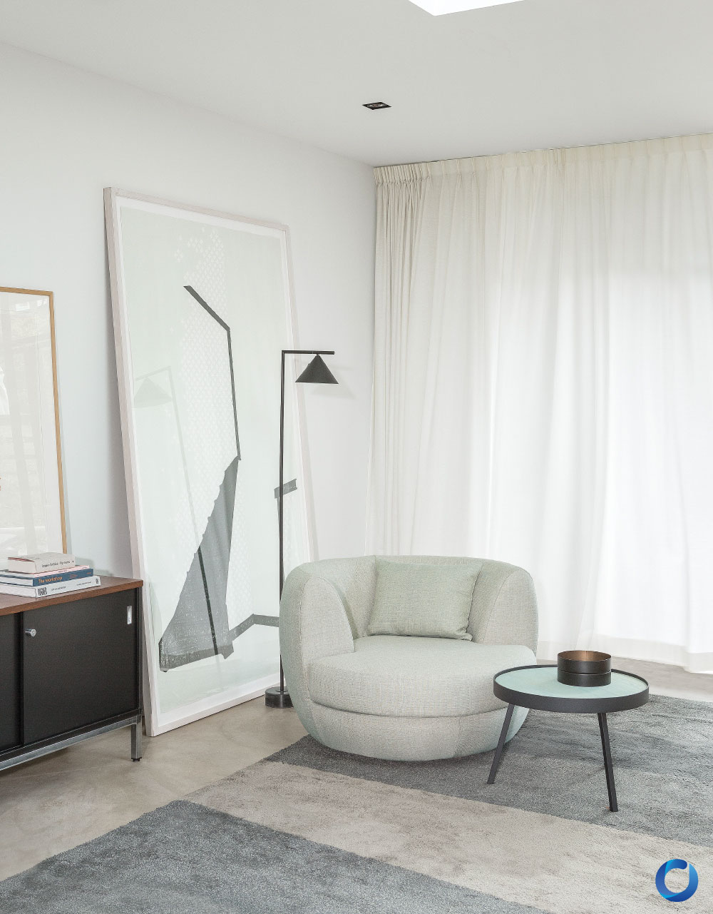 Minimalist corner with light gray armchair, sheer curtains, and modern decor. Gent Collection