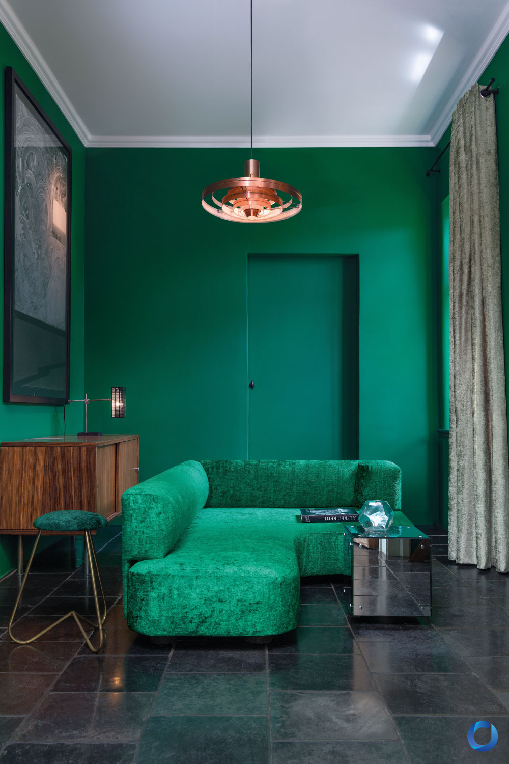 Luxurious green velvet sofa in a bold emerald-themed living room. Features rich textures, modern furniture, and elegant lighting for a sophisticated interior design. Brigadier Collection