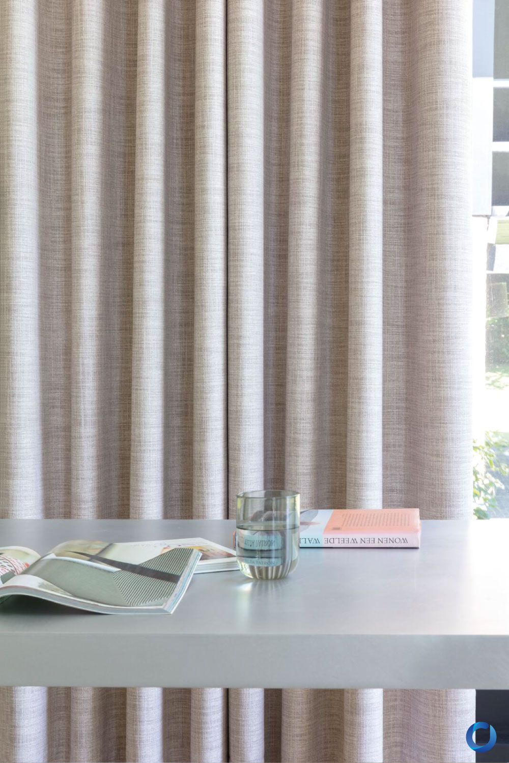 Neutral textured curtain fabric behind a modern reading table. Collection Malta