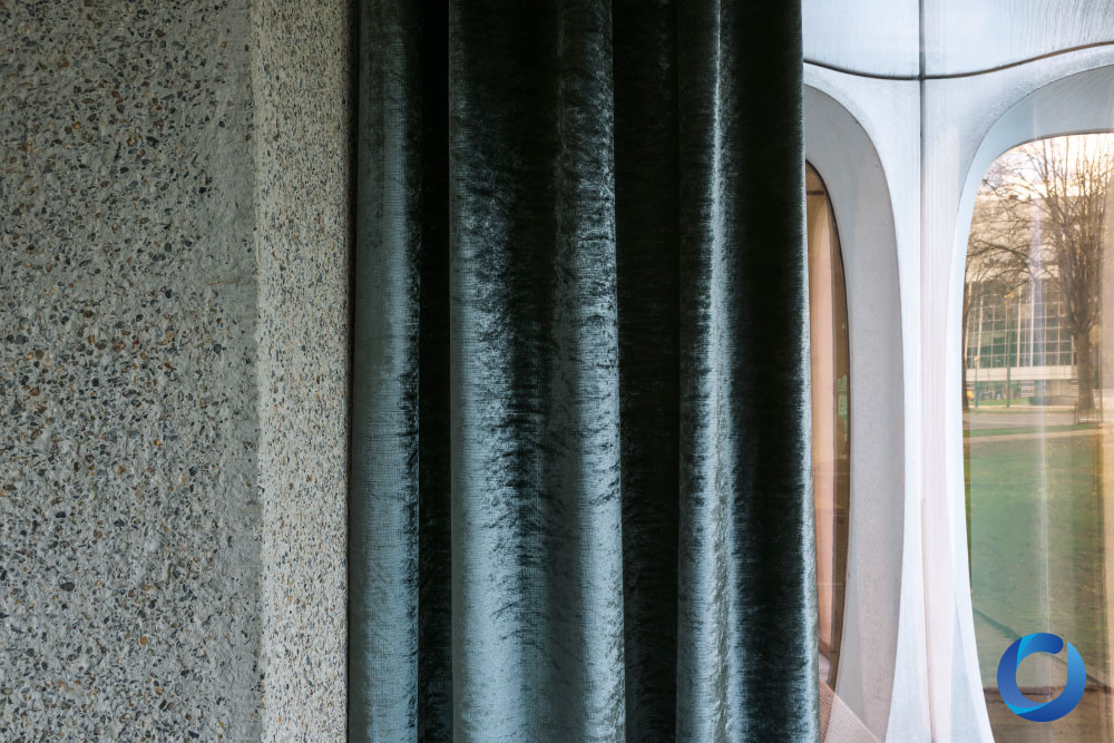 Dark velvet curtain beside textured concrete and modern glass window. Osiris Collection