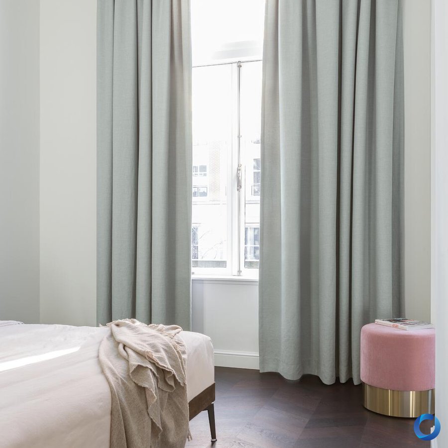 Soft grey dim-out curtains in a bright bedroom with natural light, Eris design from Night Sky collection by Acacia Fabrics