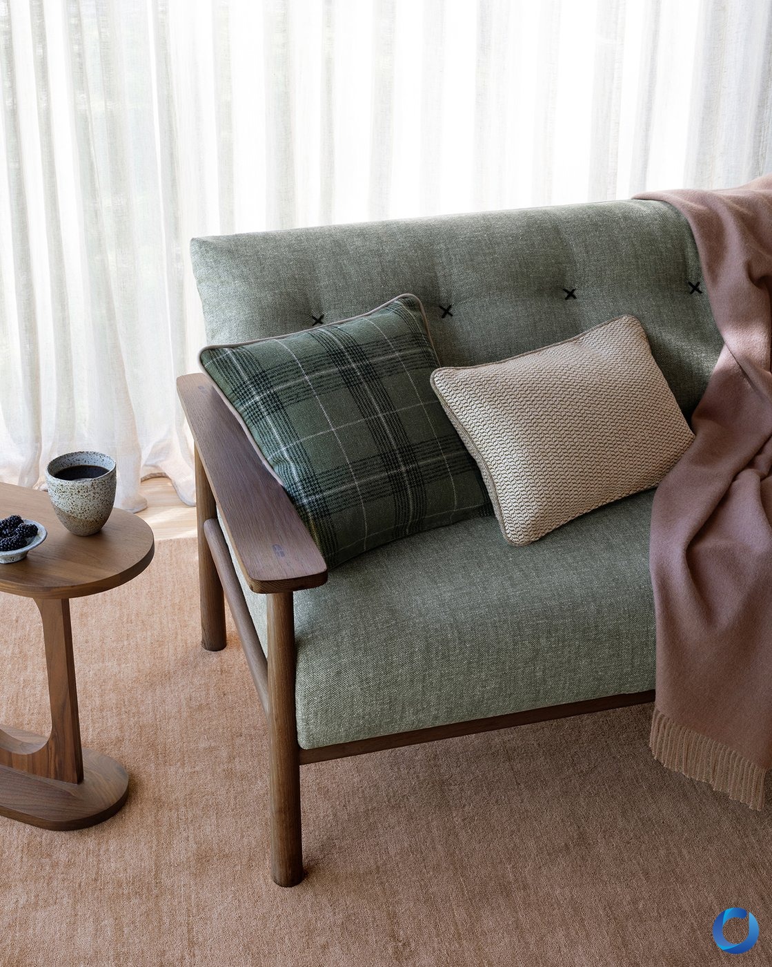 Sage green tufted armchair with checked and woven cushions against a sheer curtain, James Dunlop Hinterland collection