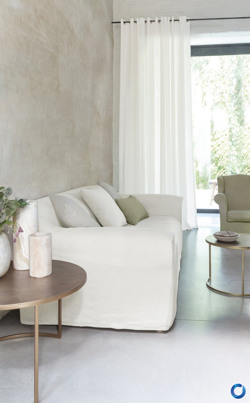 Off-white slipcover sofa beside a sheer eyelet curtain in a neutral, textured living space, James Dunlop Soho collection