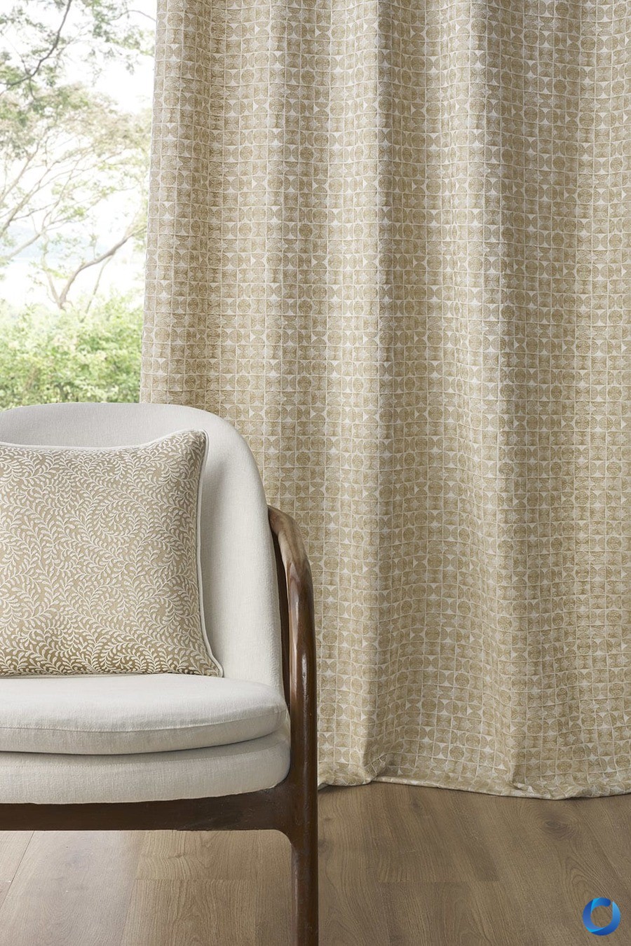 Geometric woven curtain in soft beige tones beside a cream armchair with a matching patterned cushion, Sansaar Wovara collection
