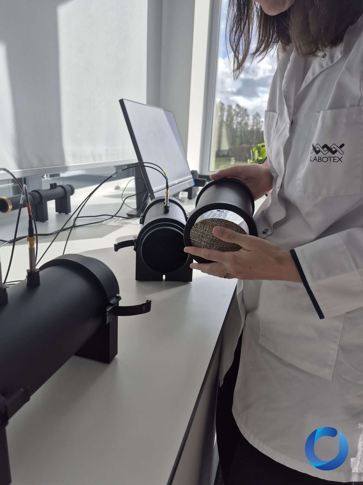 Labotex technician loading a woven fabric sample into an impedance tube for acoustic testing
