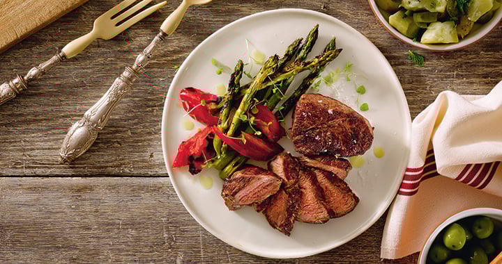 Grilled lamb steaks with a warm salad of mashed new potatoes green olives and fresh herbs