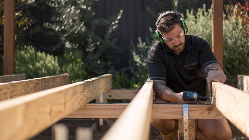 Using a nail gun to attach nails to metal support brackets