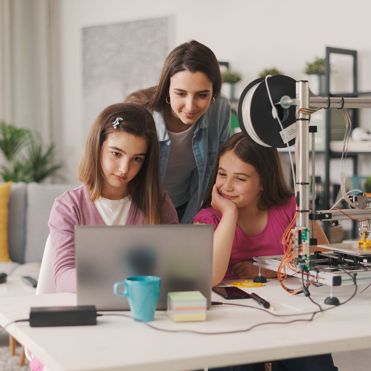 Teacher guiding two students working on a laptop