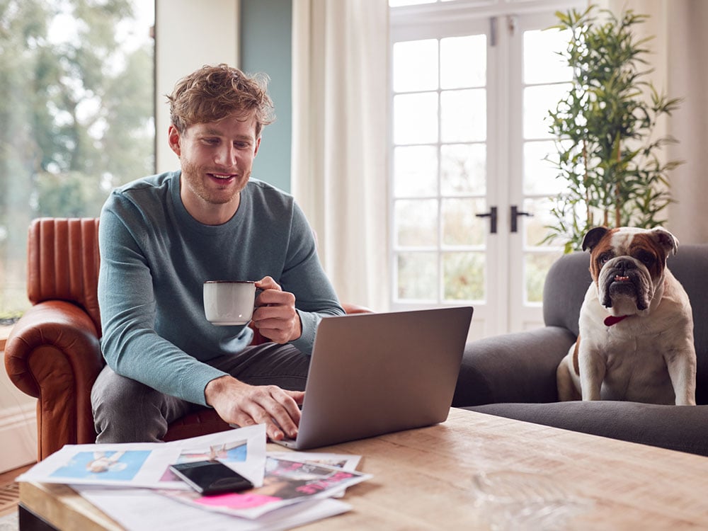 Person with cup watching laptop