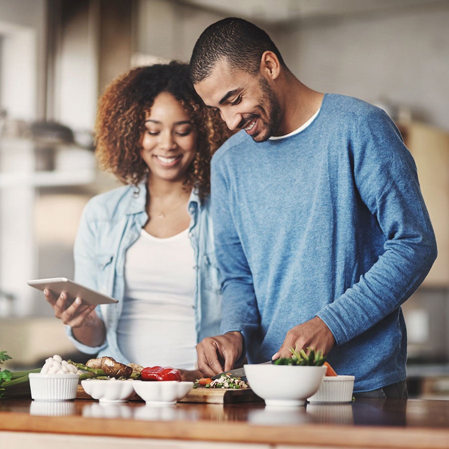 Couple Watch On Mobile Device While Cooking