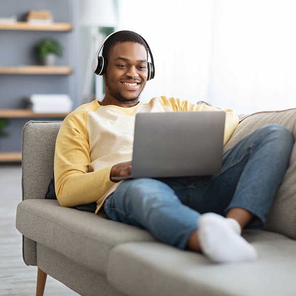 Man sitting on the couch and watching videos on laptop