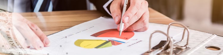 Person writing on paper with a pie chart
