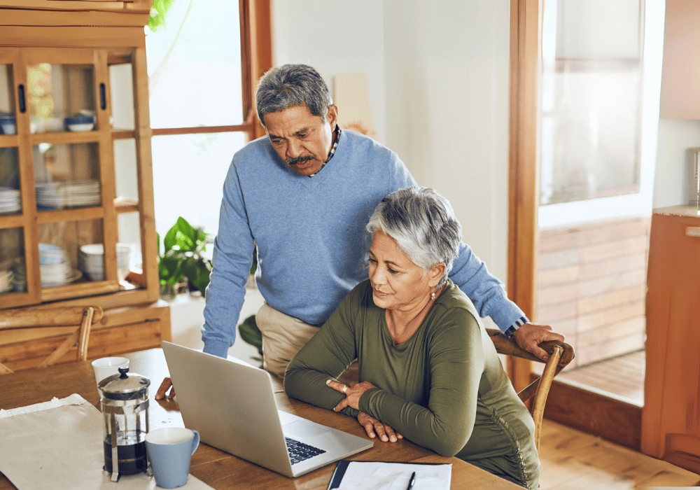 Retirees sitting at the desk talking while looking at the laptop