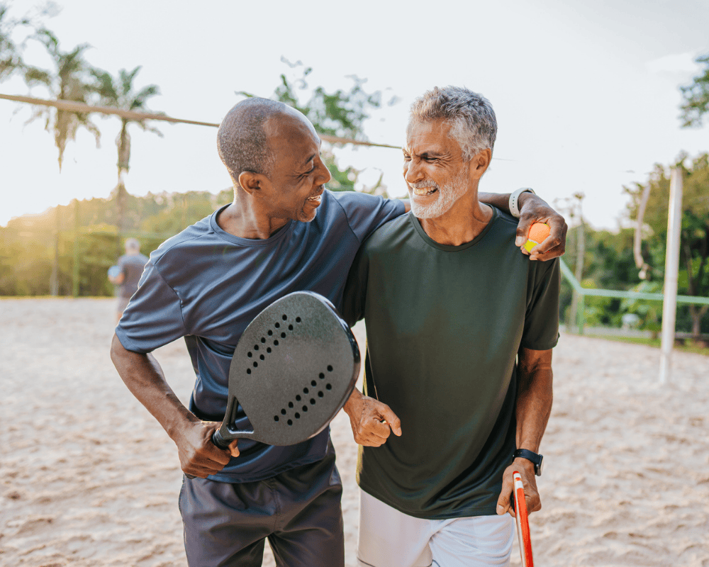 Two senior friends playing beach tennis