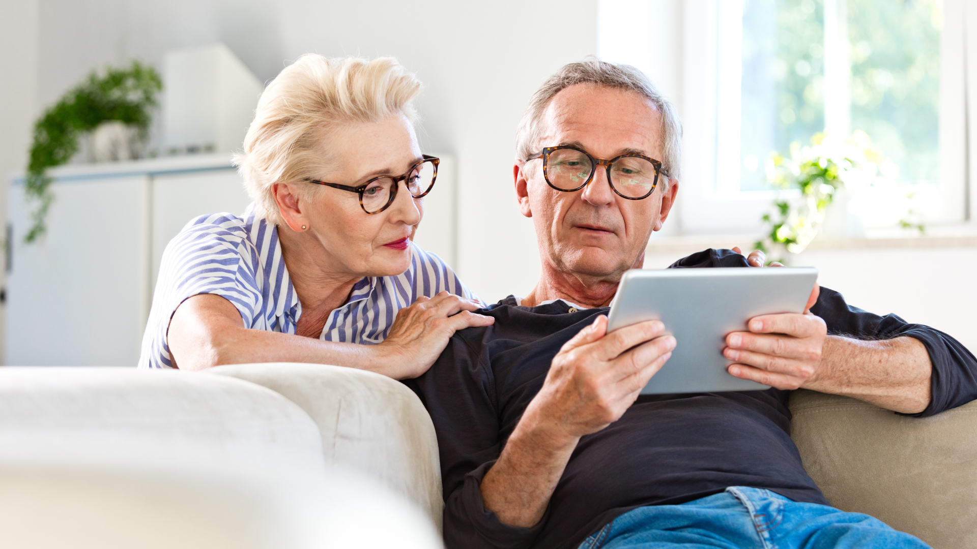 retired couple on lounge looking at an ipad