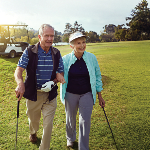 Retiree golfing couple walking on golf course