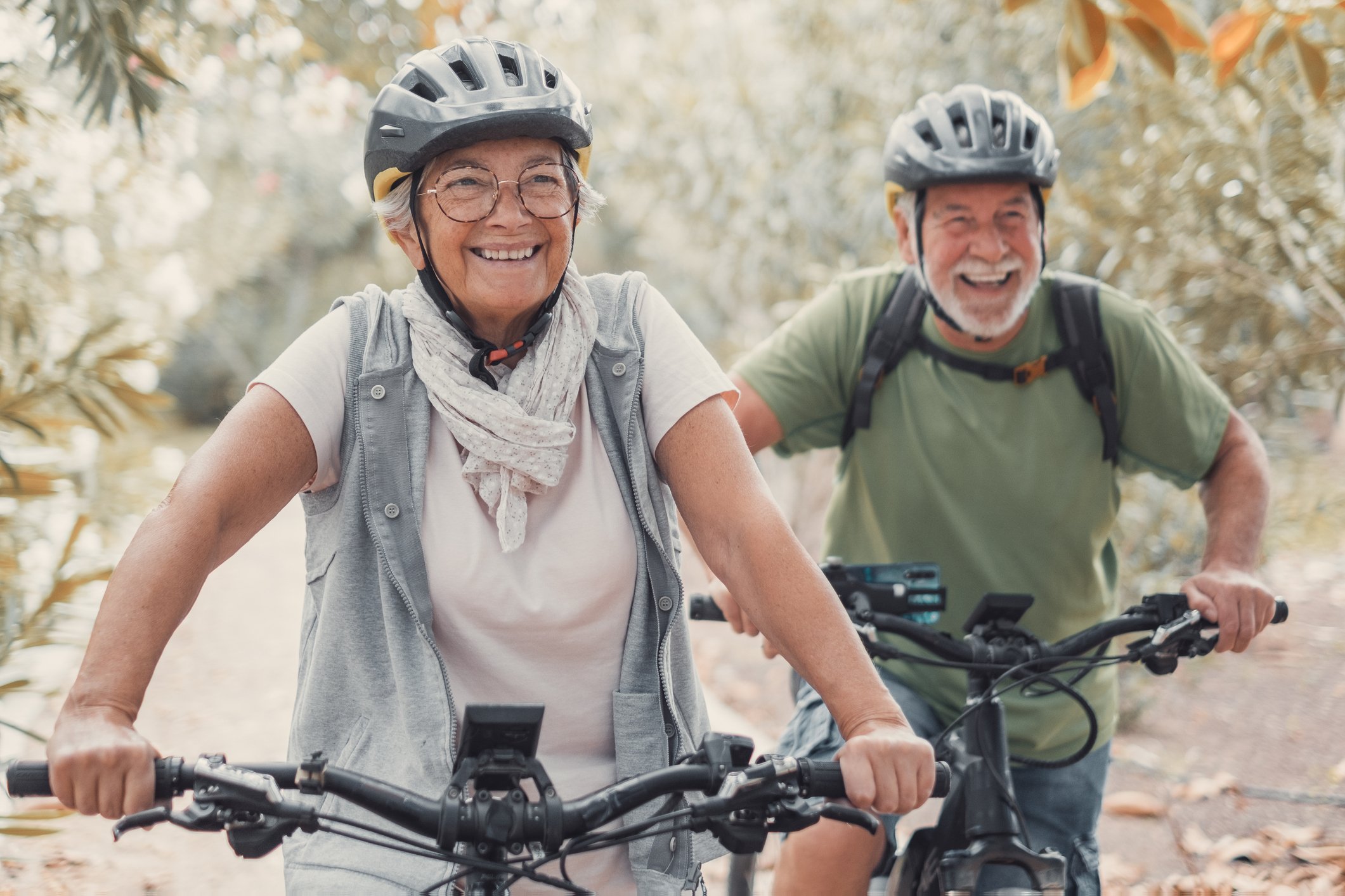 Two happy old mature people enjoying and riding bikes together to be fit and healthy outdoors