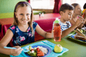 Young girl sitting at lunch eating and drinking