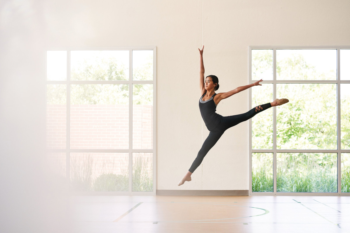 Ballerina girl leaping above a dance floor.