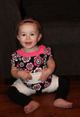 girl sitting on ground smiling with hip abduction brace on