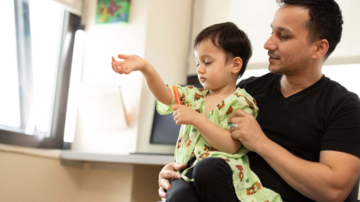 father holds son who's wearing hospital gown