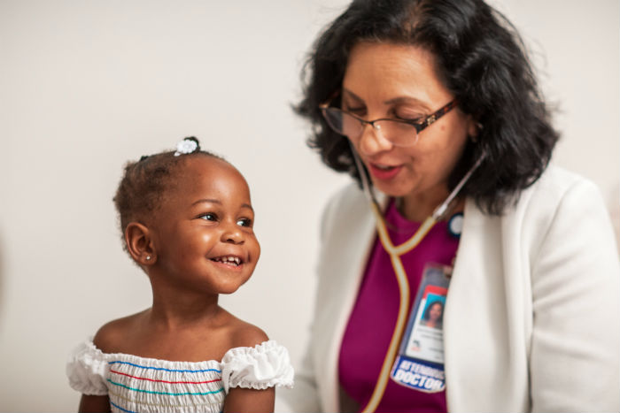 Doctor listening to heartbeat of little girl