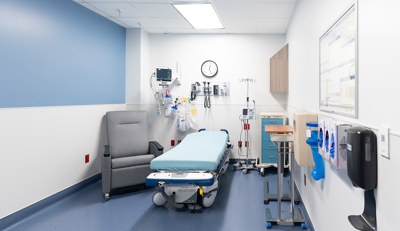Small patient room with a bed and a chair for support individuals. 
