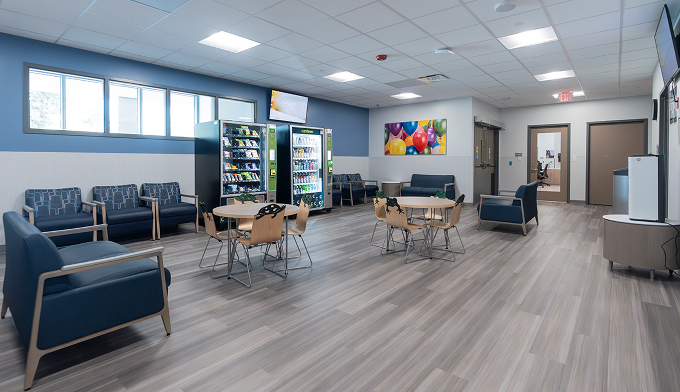 Patient waiting area with tables, chairs and vending machines.