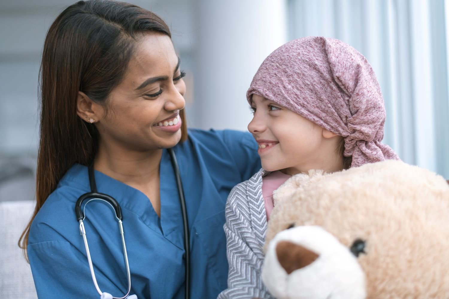 Doctor smiling at young patient holding a teddy bear