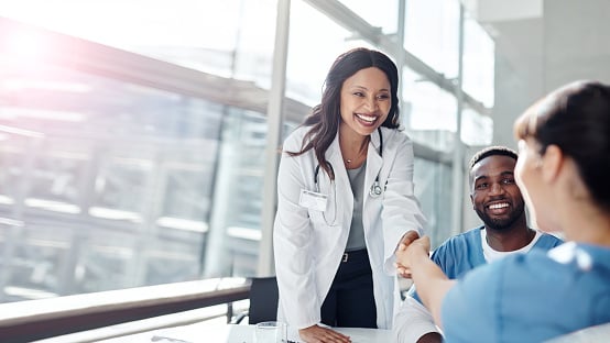 A provider delightfully shaking hands with a woman.