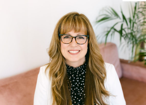 Lori Irvin sitting in a chair with a plant in the background