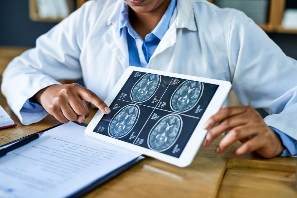 A doctor shares a scan of a brain on a tablet in a patient consultation