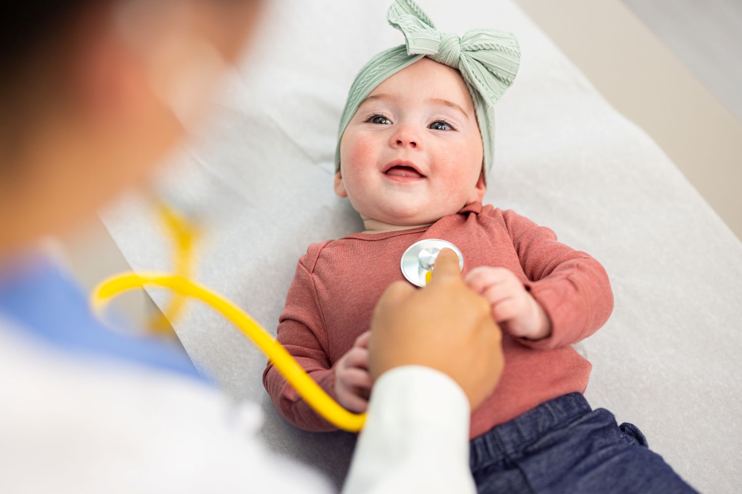 Doctor using a stethoscope on a smiling infant