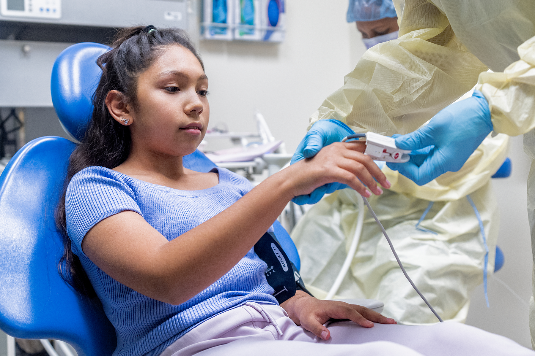 Pre-teen sitting in dentist chair getting heart rate, blood pressure and pulse ox checked. 