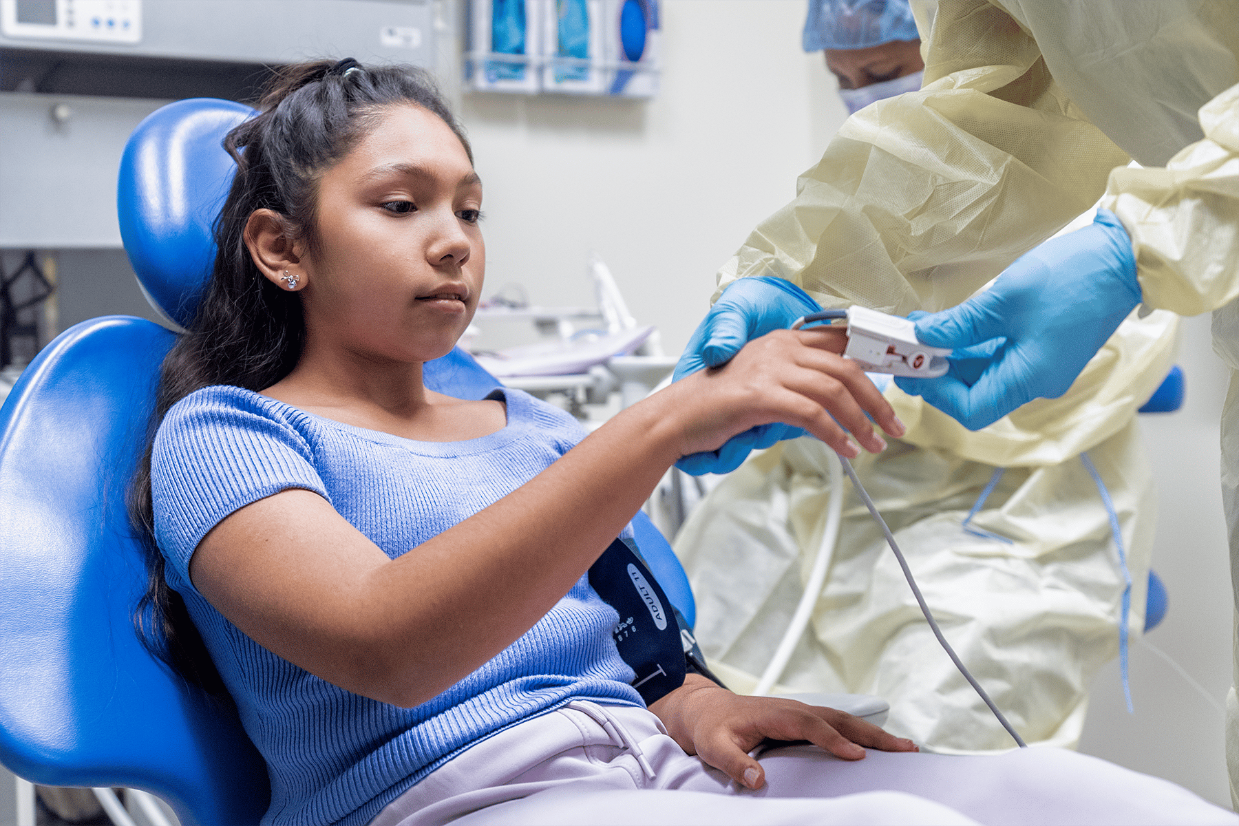 Pre-teen sitting in dentist chair getting heart rate, blood pressure and pulse ox checked.