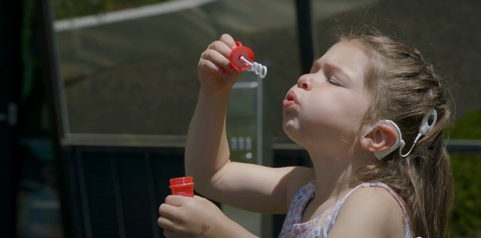 Girl with cochlear implant blowing bubbles