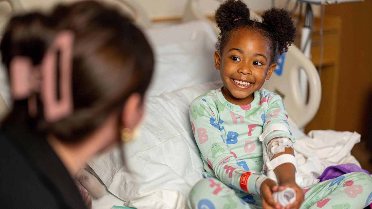 young girl smiling in hospital bed