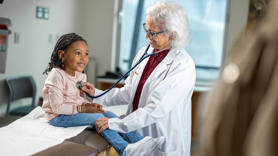 Children's National nephrologist Asha Moudgil, M.D., listens to the heart of a little girl.