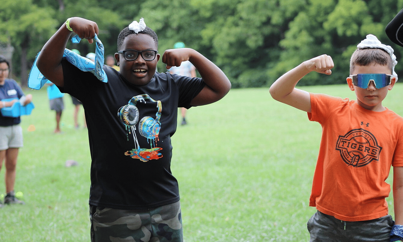 Two school age boys playing outside showing their arm muscles
