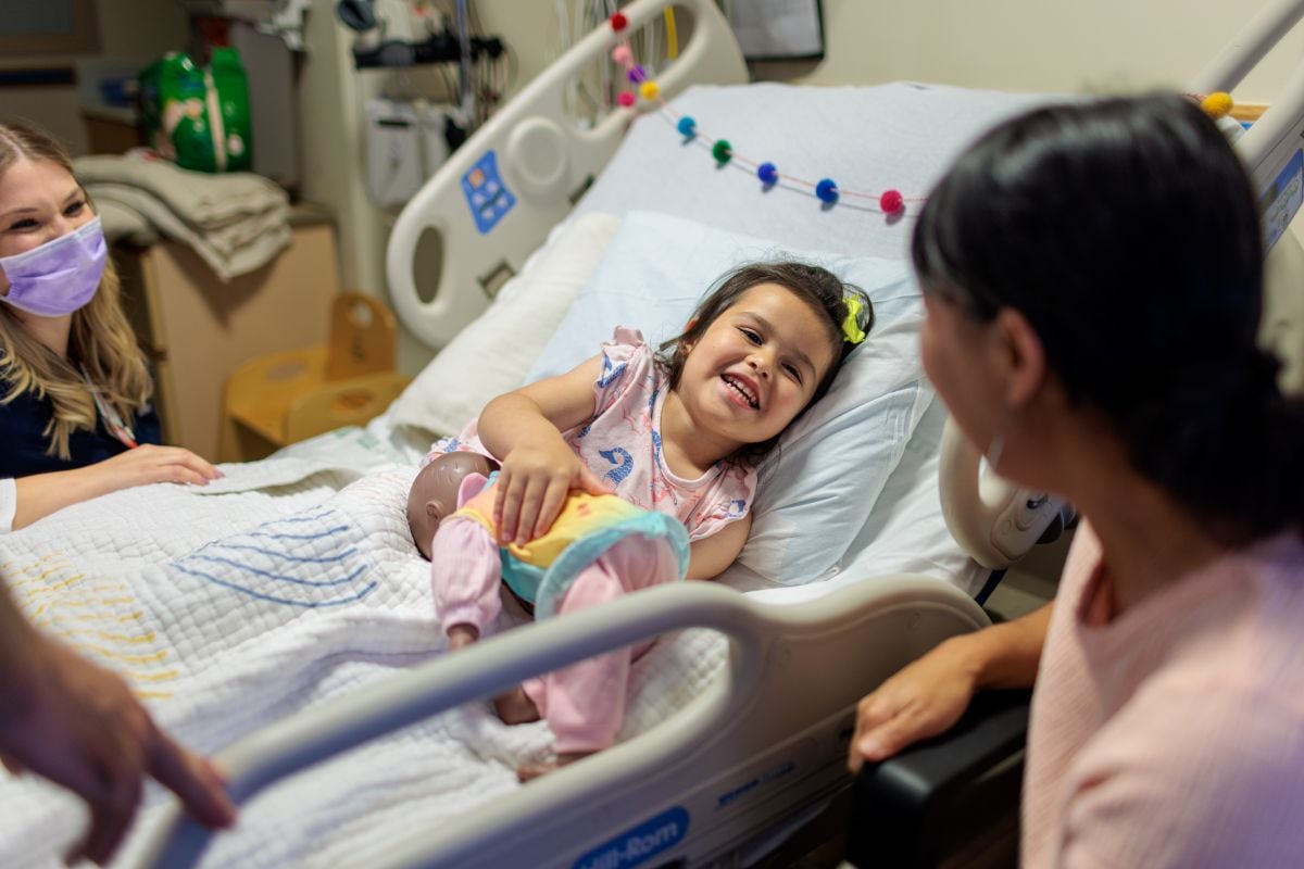 Paciente joven en la cama riendo con su familia y el personal