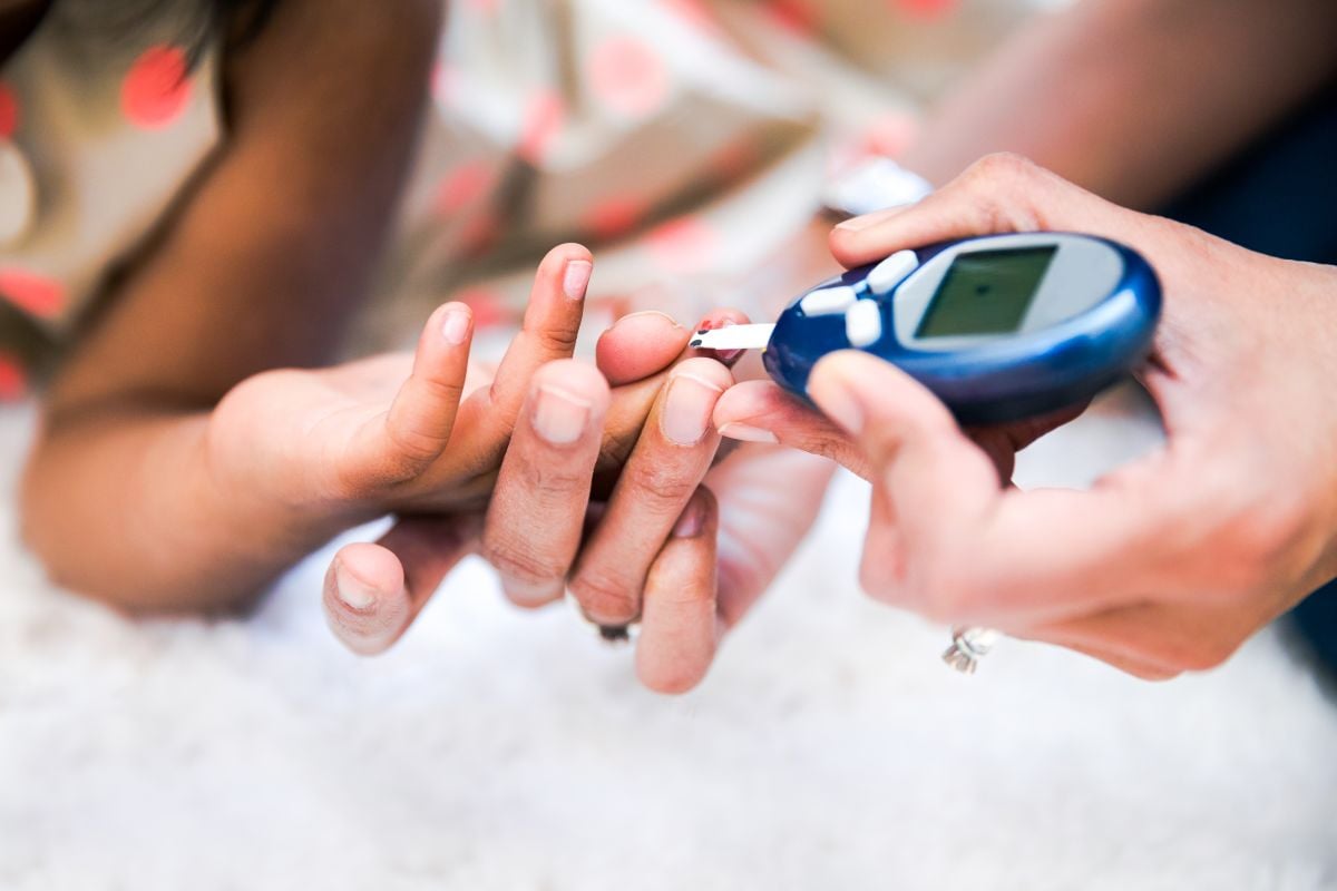 Una madre está controlando la diabetes de sus hijas controlando el nivel de glucosa en sangre