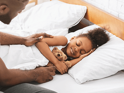 dad covering his sleeping daughter