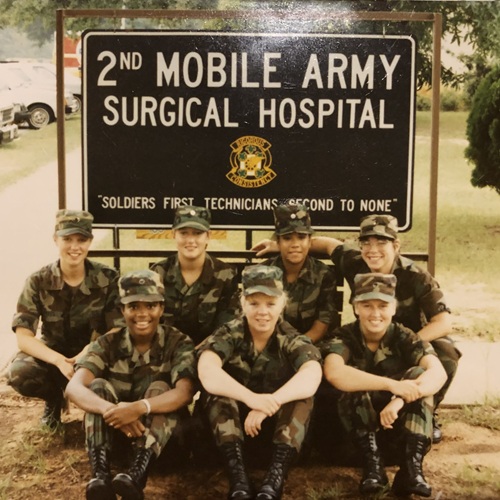 Jean Fletcher, a nurse in the Army, pictured with a group of soldiers in front of an Army surgical hospital sign