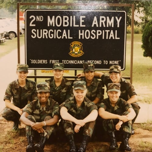 Jean Fletcher, a nurse in the Army, pictured with a group of soldiers in front of an Army surgical hospital sign